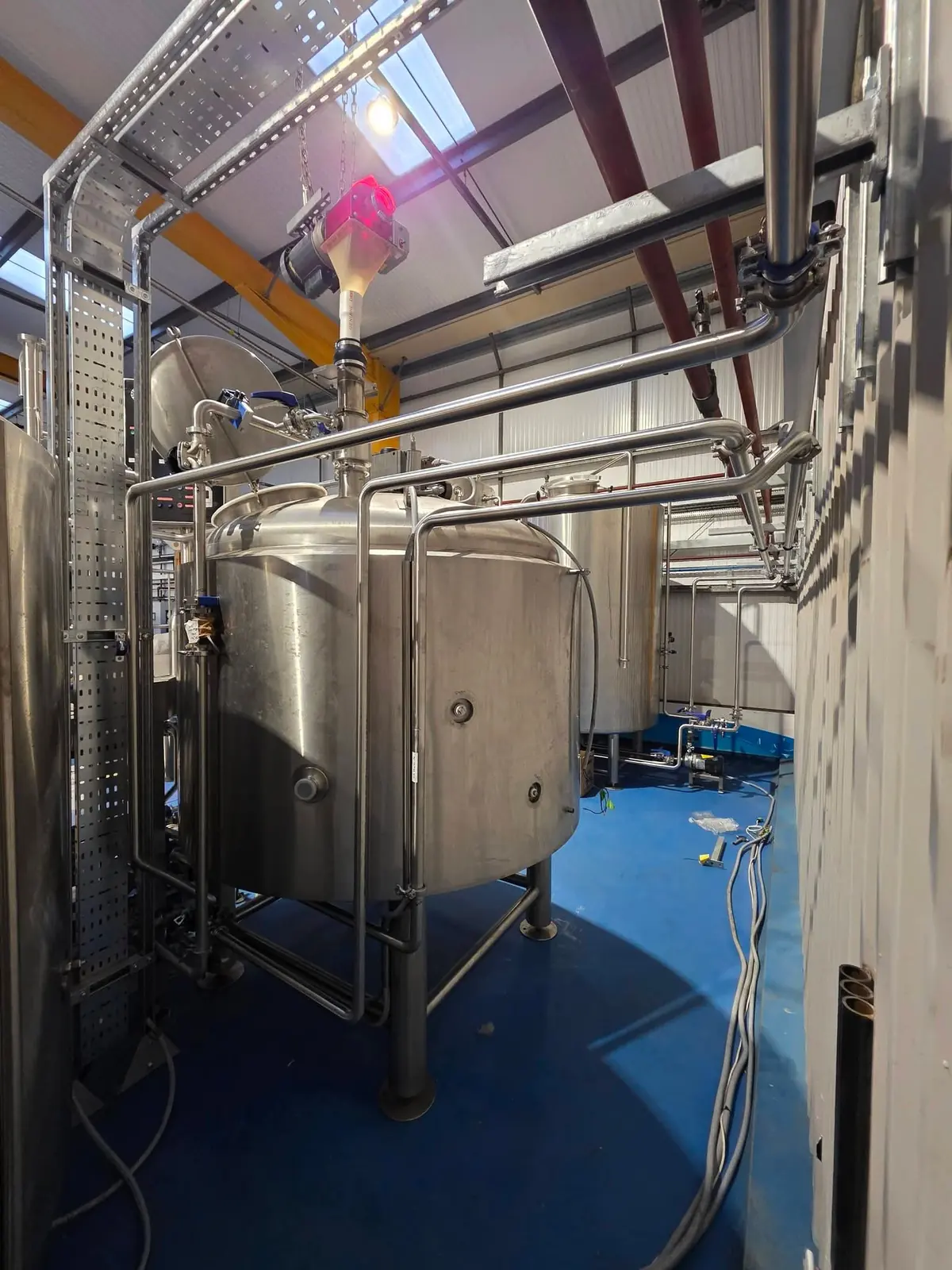 Stainless steel brewery vessel with hygienic pipework running overhead