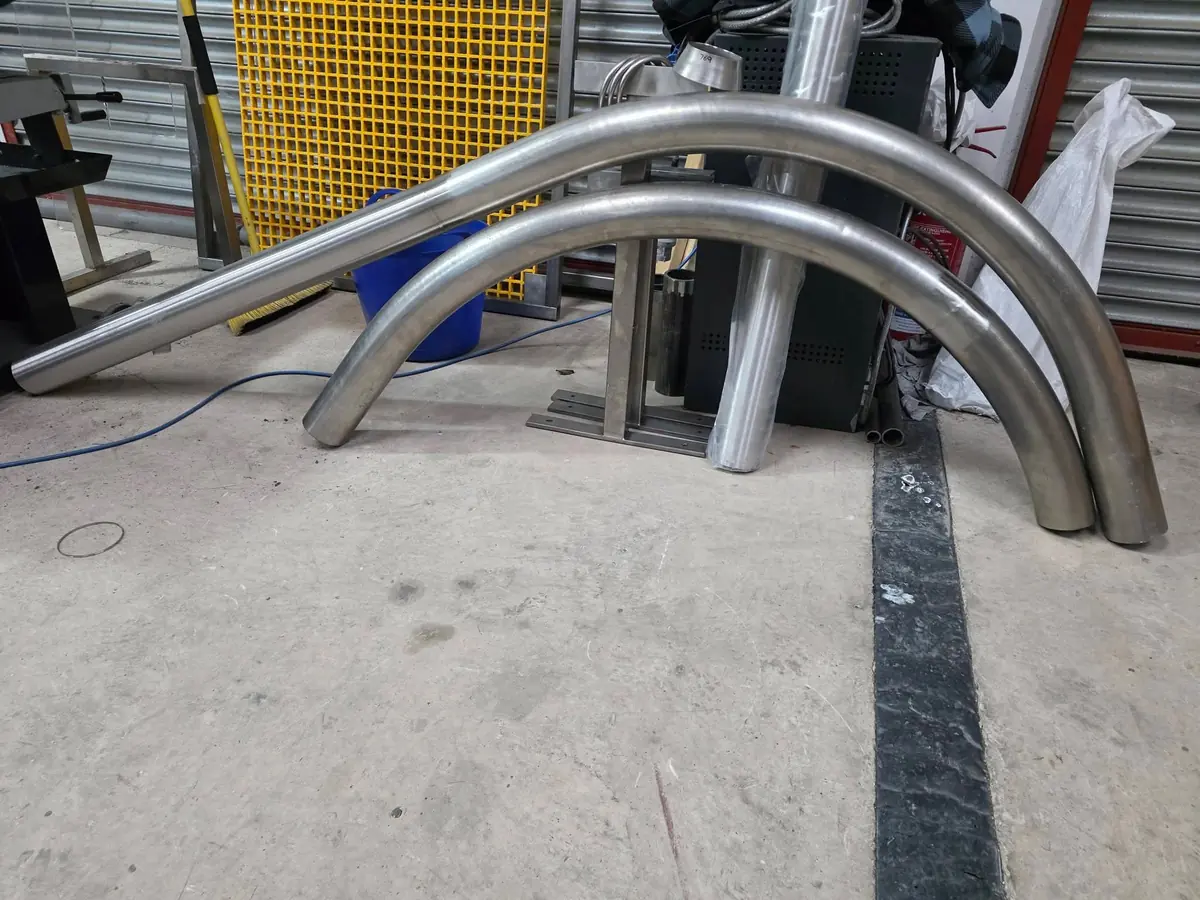 Large radius stainless steel pipe bends laid out in the workshop