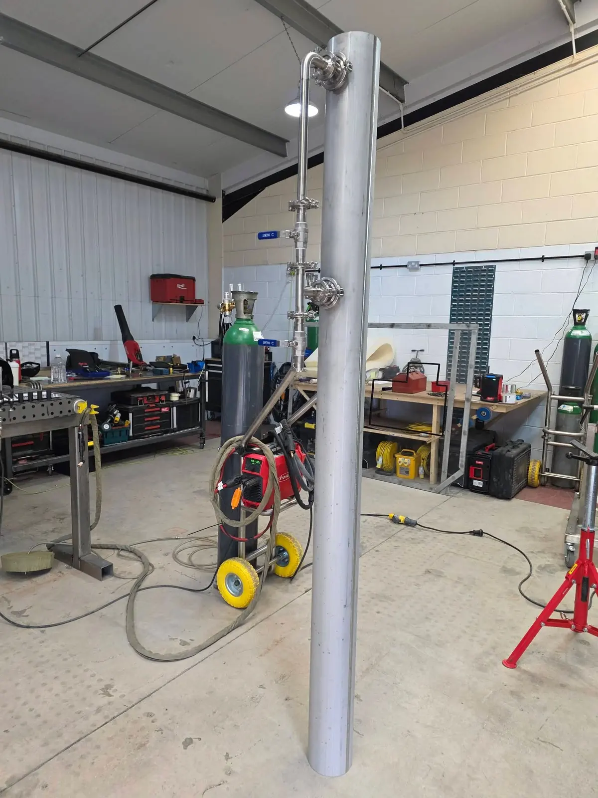 Prefabricated stainless steel silo intake pipework with valves and tri-clamp joints on a workshop jig