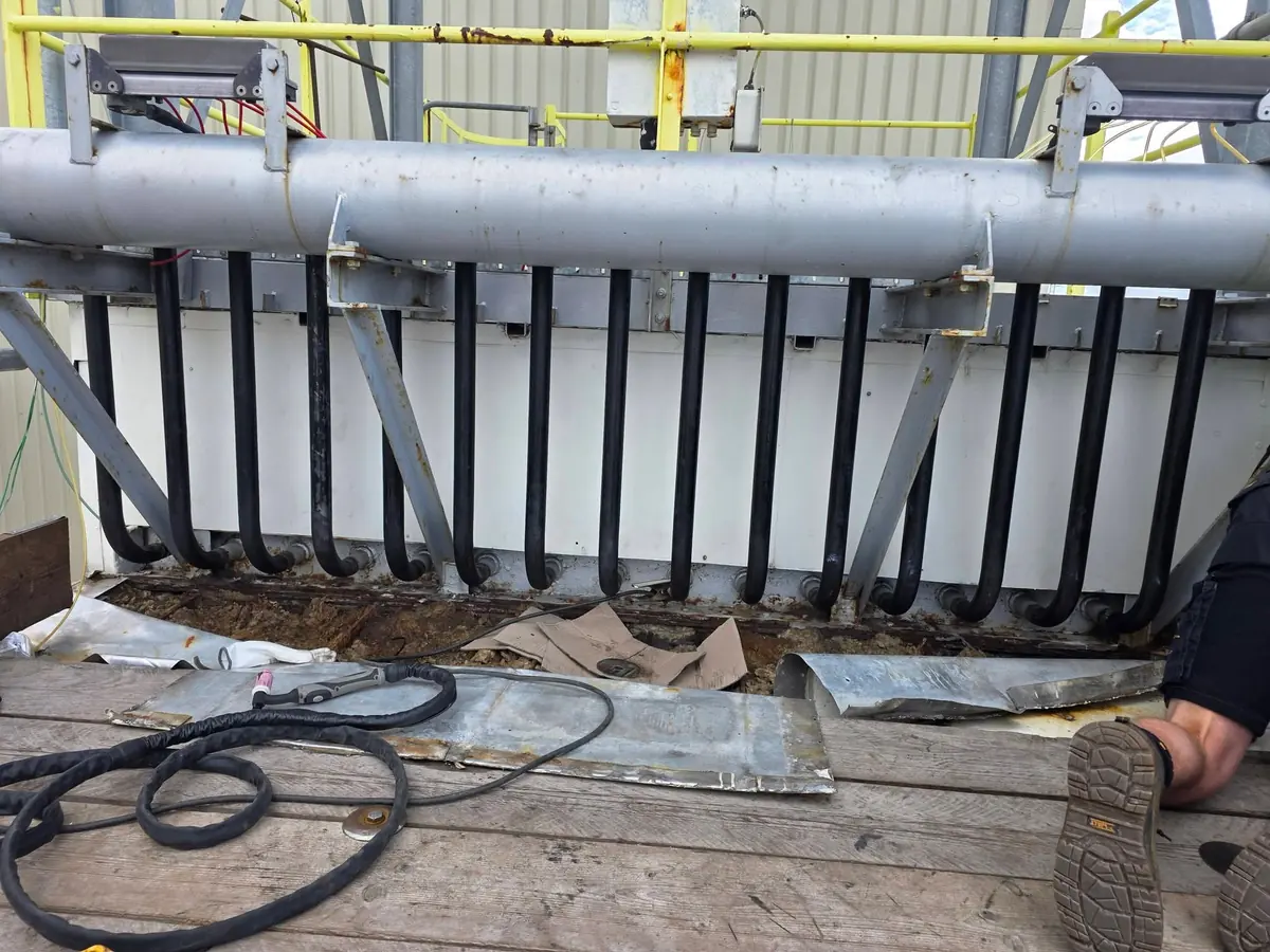 Row of new black blowdown tubes installed along a heat exchanger during a shutdown