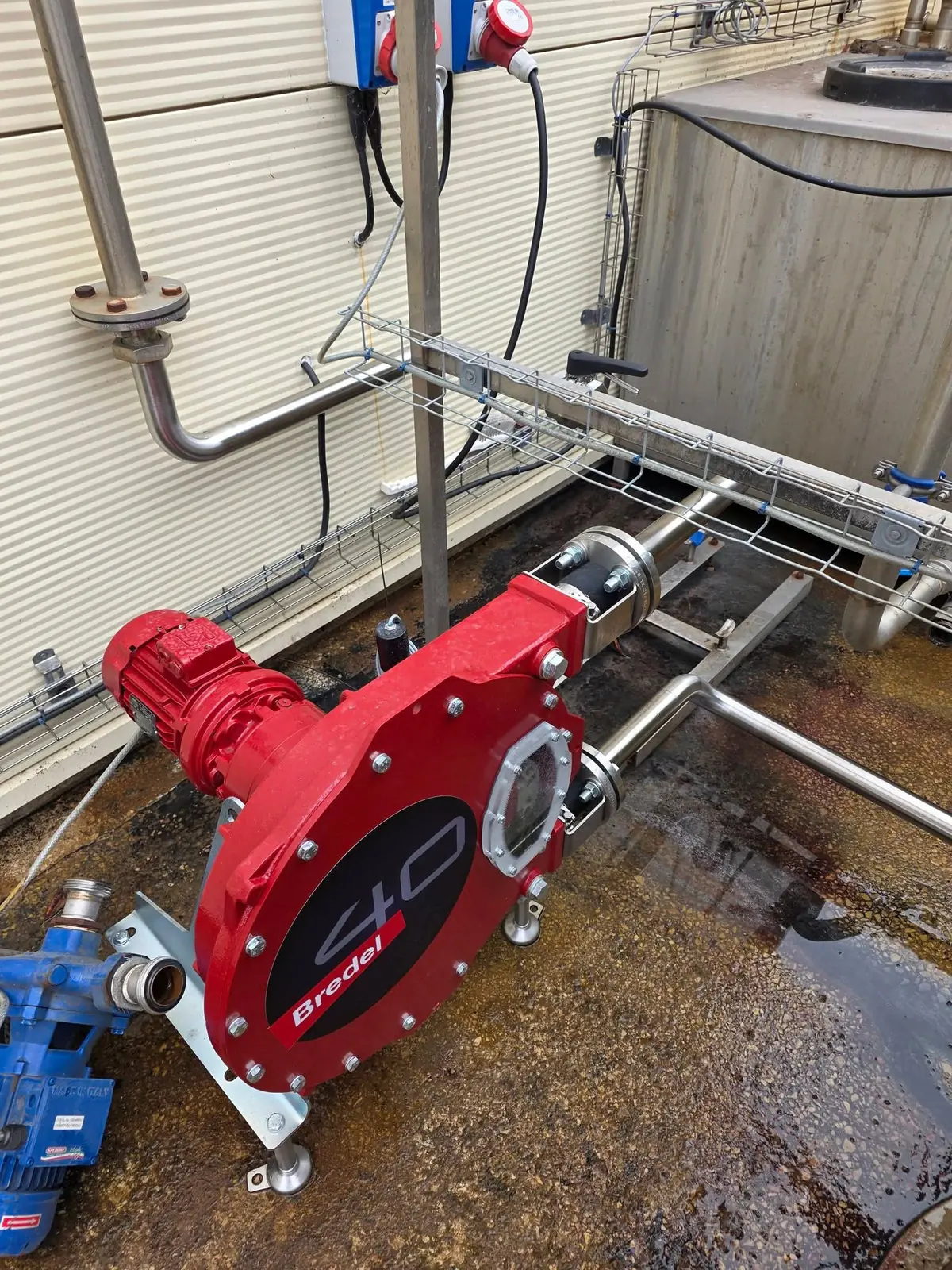 Red peristaltic pump with stainless steel pipework and flanged connections