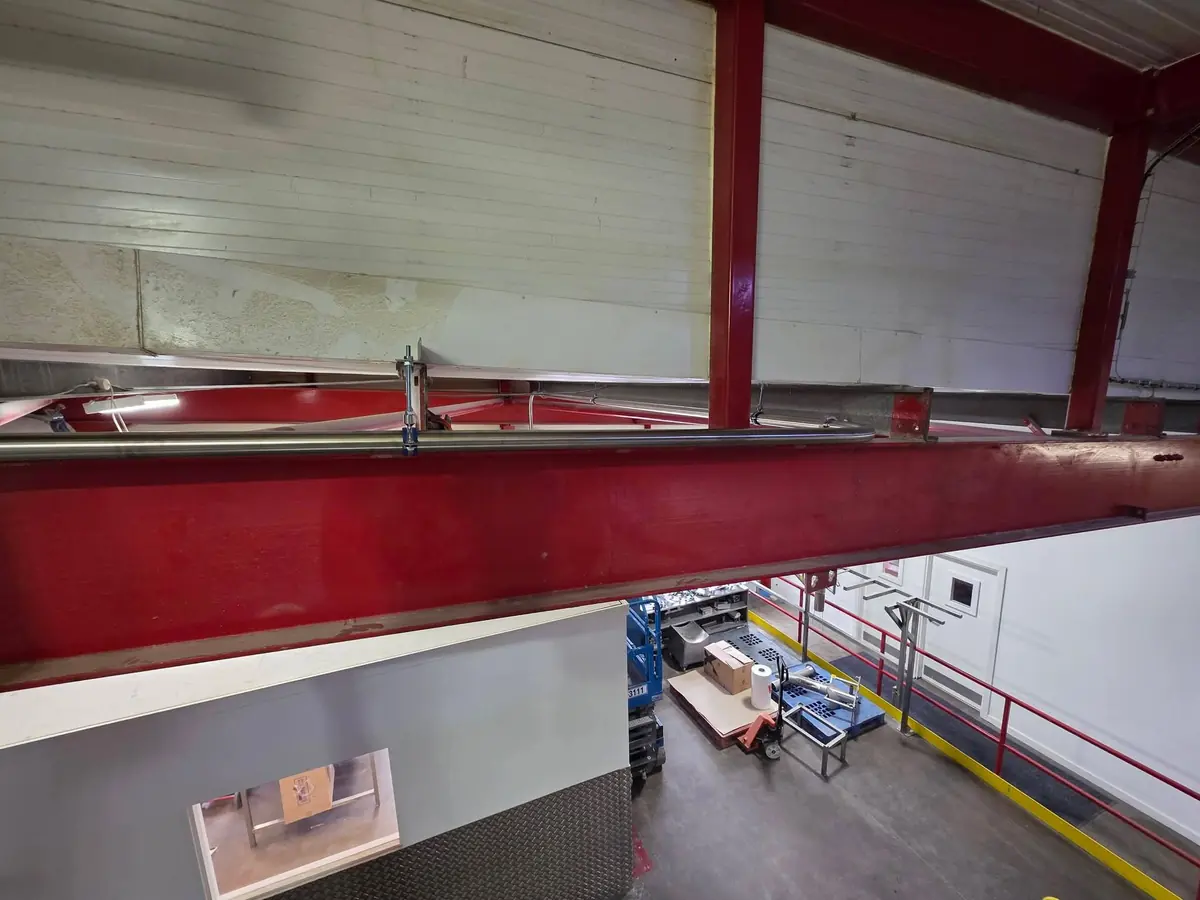 Stainless steel vacuum line routed along a steel beam