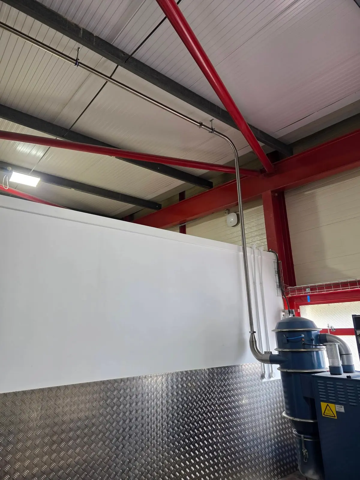 Stainless steel vacuum line running overhead and down to a blue vacuum unit