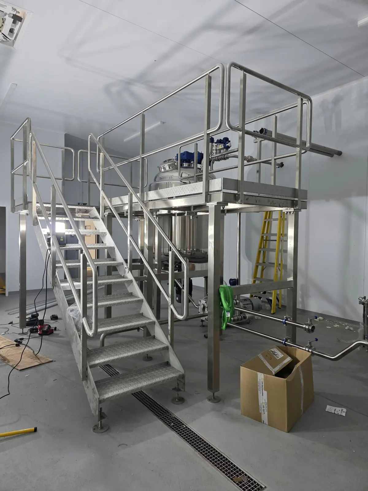 Stainless steel access platform with staircase and handrails built around a process vessel